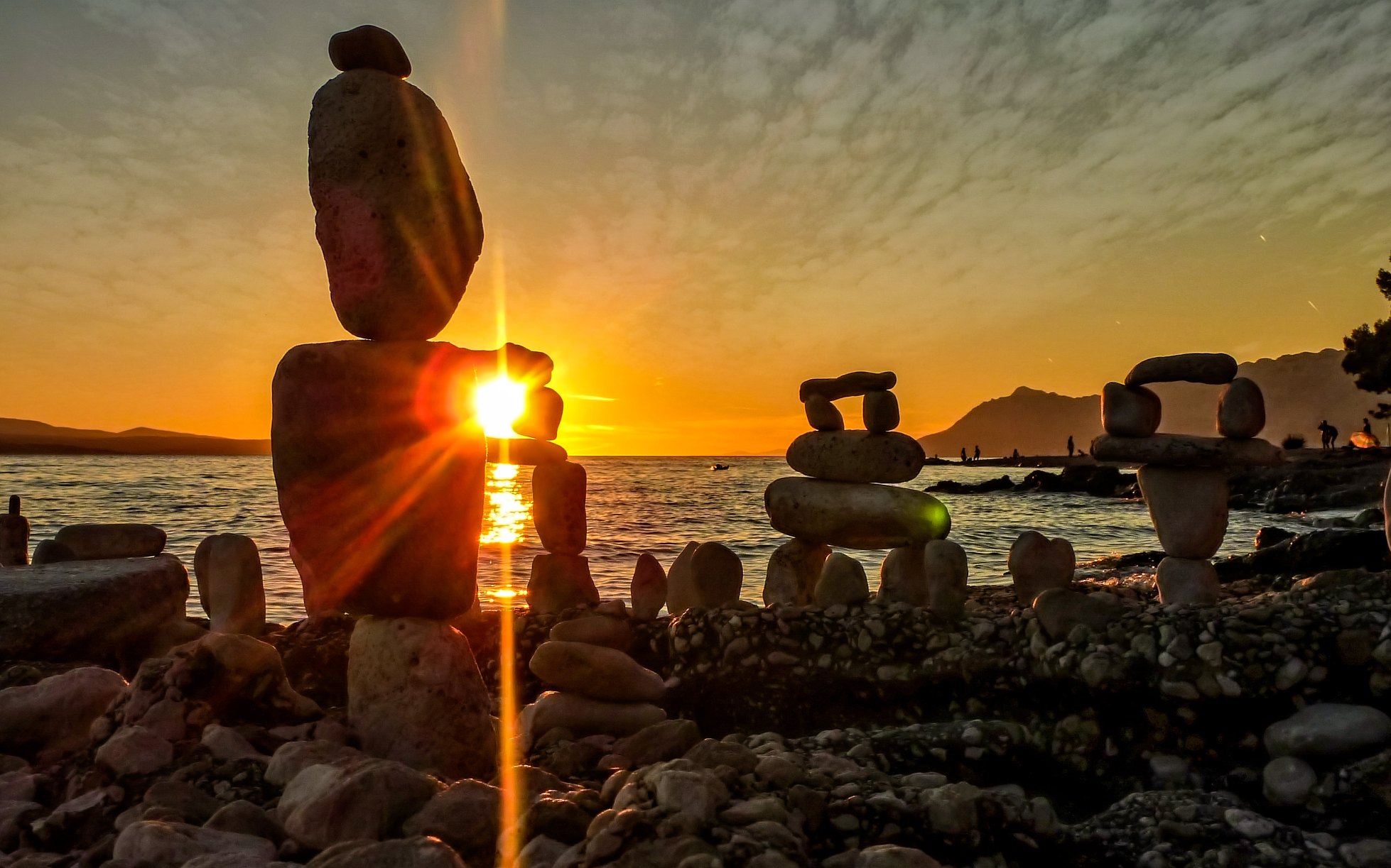 Steinfiguren am Meer bei Sonnenuntergang